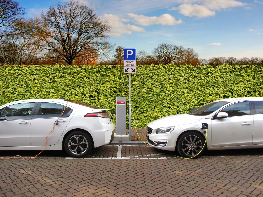 Two electric cars parked up and plugged into charging points.