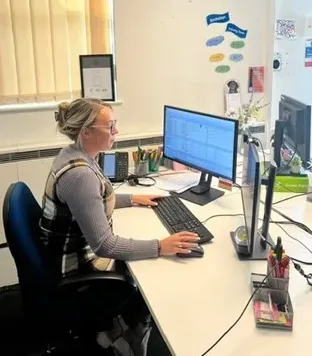 A side profile of Nicole working on her computer in the office.