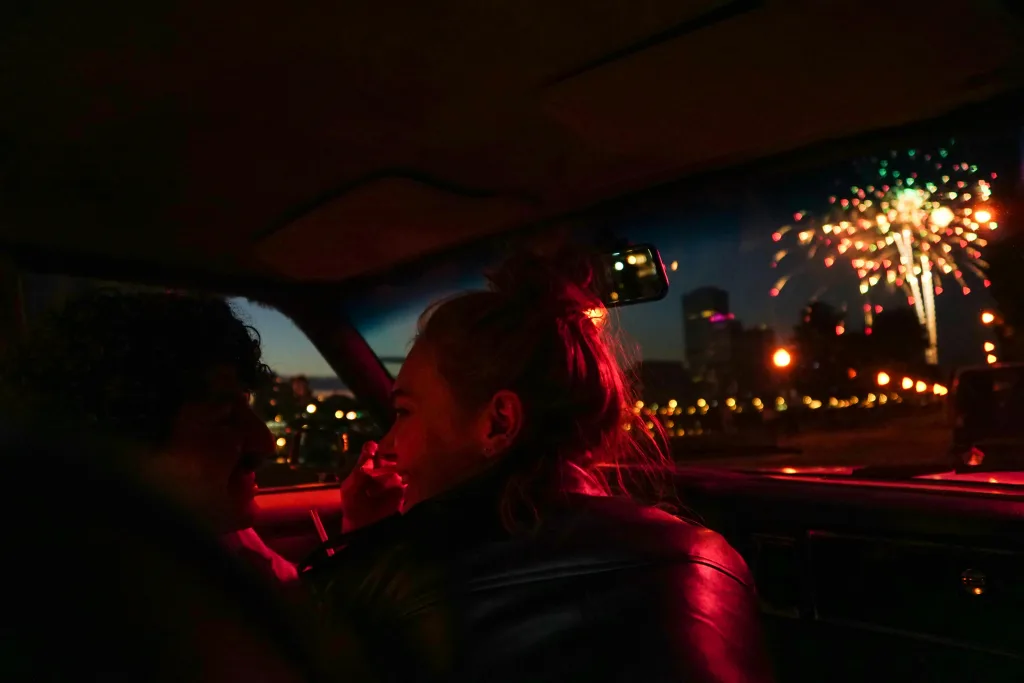 A couple watching fireworks from their car