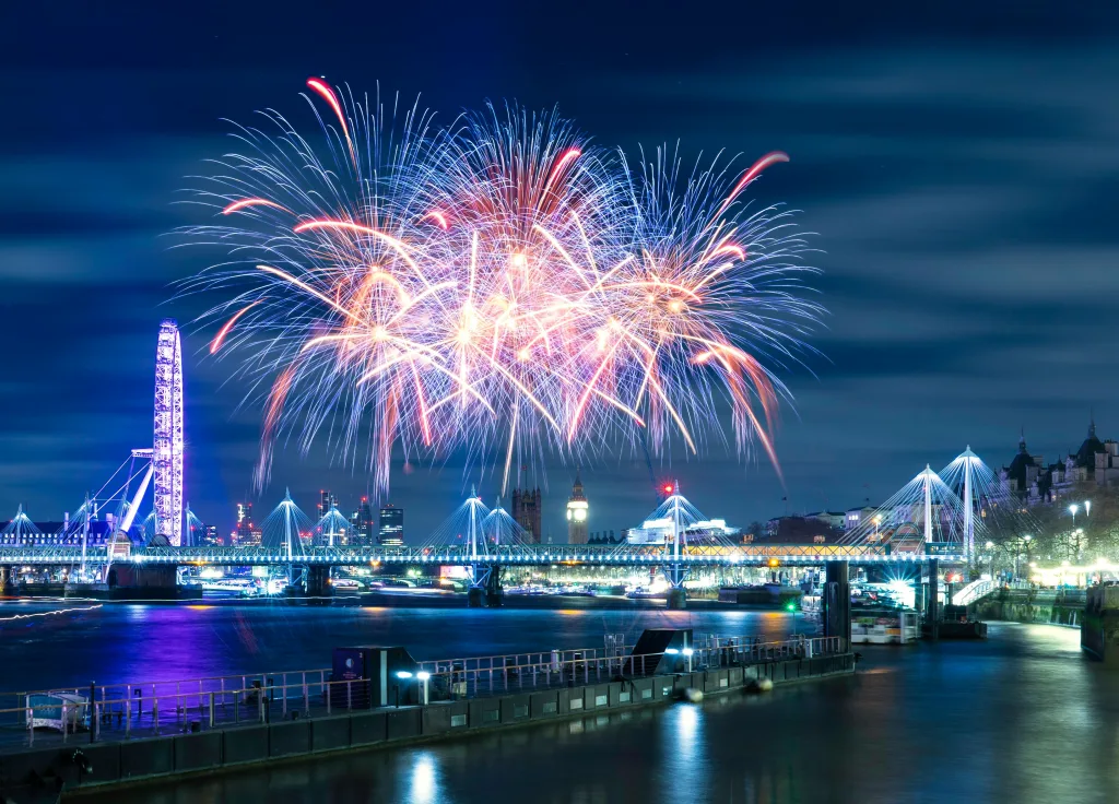 Fireworks exploding across the London skyline at night.