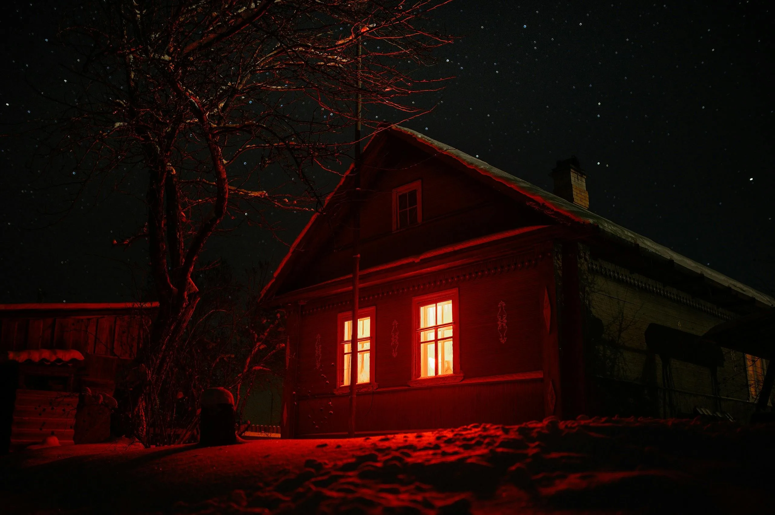 A house glows red in the dark from an orange light emanating from the windows