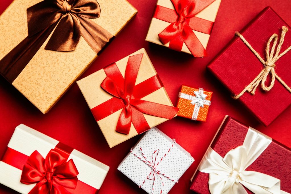 A bird’s eye view shot of a red backdrop with a selection of gifts in silver, gold, and red wrapping paper and ribbons.