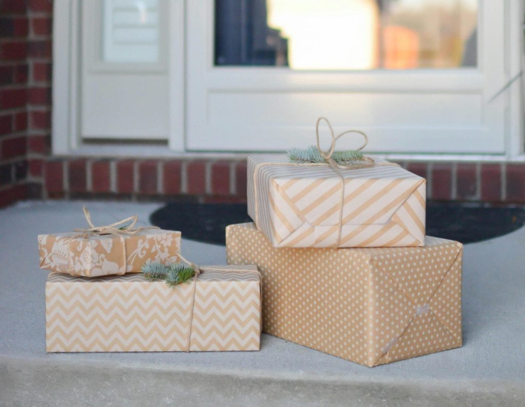 A pile of beige and white Christmas gifts on a front doorstep.